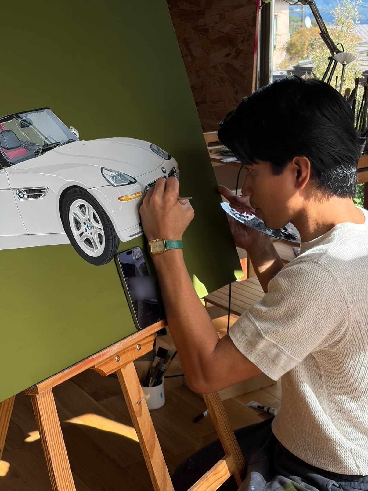 アトリエで白いBMW Z8を描く作家